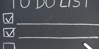 An einer Tafel steht die Überschrift „TO DO LIST”, darunter sind drei Zeilen mit Kästchen an der linken Seite und einem lange Unterstrich. In zwei Kästchen ist ein Haken gesetzt.