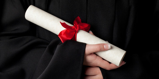 Certificate A rolled document with red bow is held by hands.