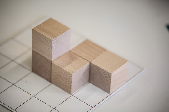 Dice math didactics Wooden bricks are built up on a checked piece of paper.