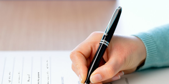 Survey A hand holding a pen fills out a survey questionnaire.